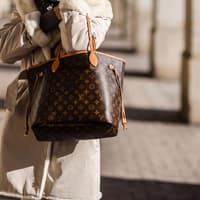 Frau in beigefarbenem Mantel mit Louis Vuitton Tasche Frau in beigefarbenem Mantel mit Louis Vuitton Tasche