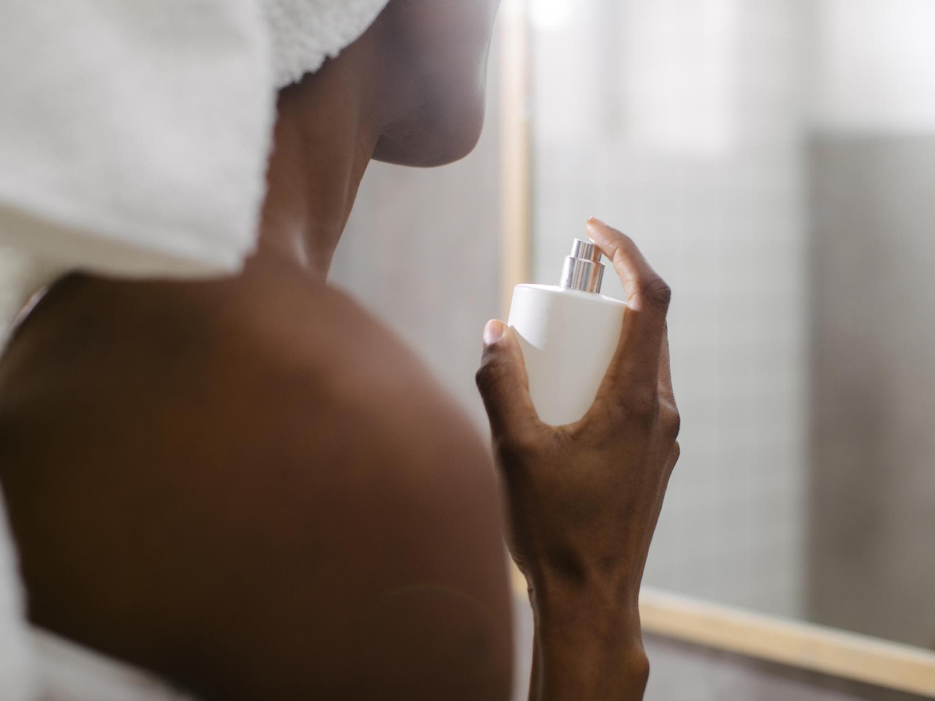 3 Parfums, mit denen du wie frisch eingecremt duftest Frau sprüht sich mit Parfum ein